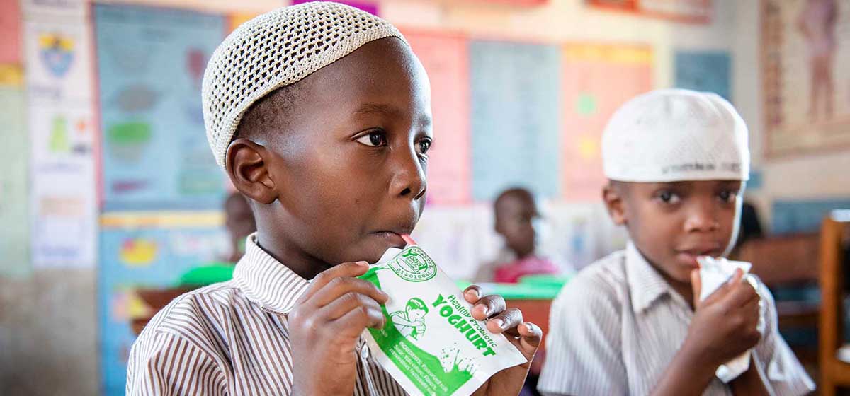 Two small African boys enjoying probiiotic yoghurt.