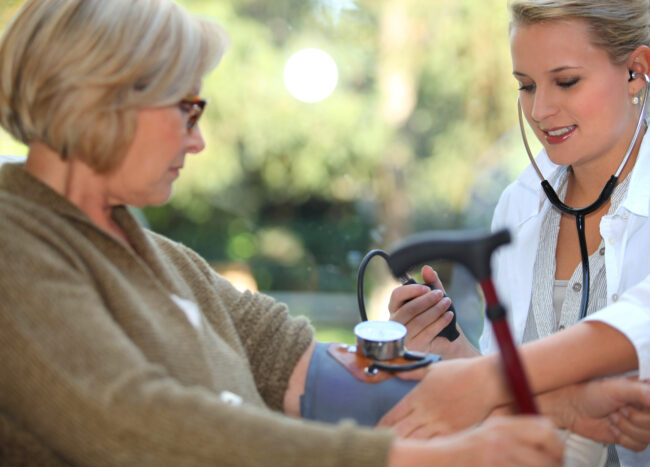 Nurse checks elders woman's blood pressure