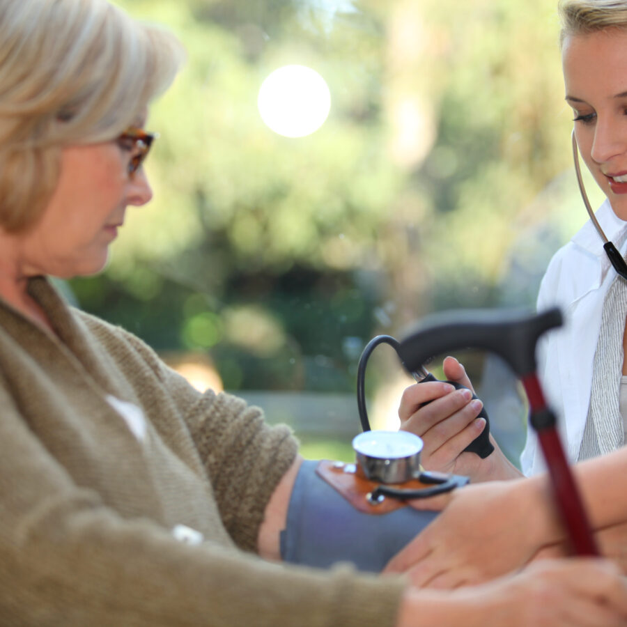 Nurse checks elders woman's blood pressure