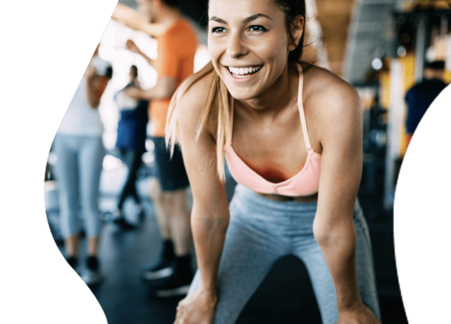 Young woman in gym, smiling.