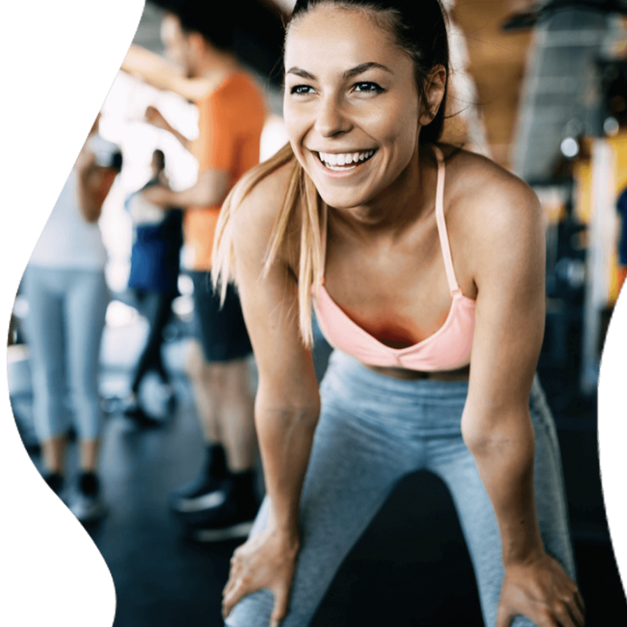 Young woman in gym, smiling.