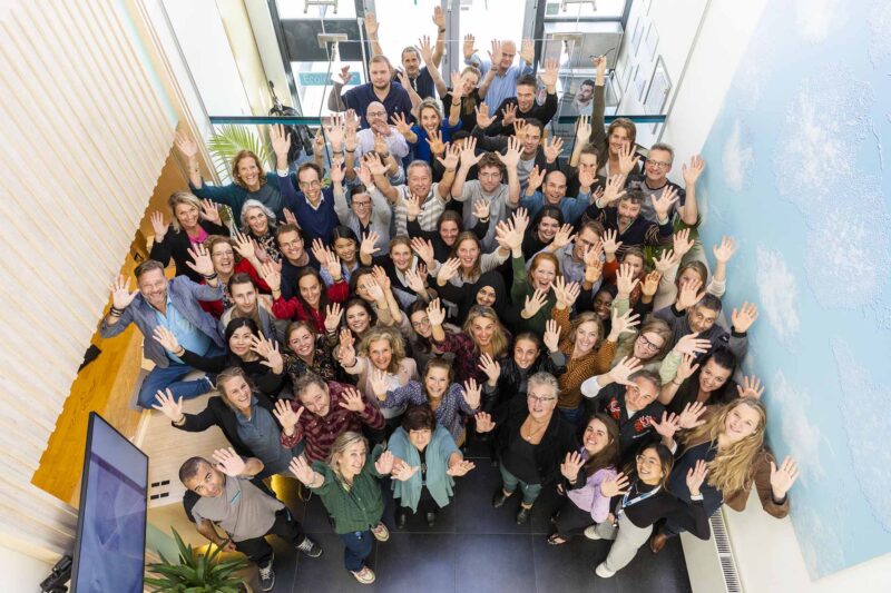 Dozens of Winclove Probiotics' employees are waving at the camera.